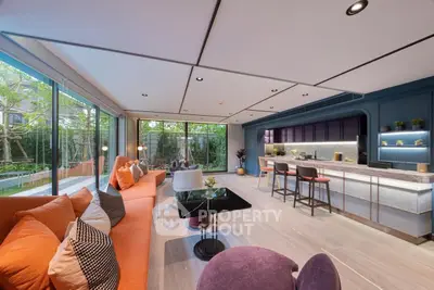Luxurious open-plan living room with modern kitchen and garden view, featuring stylish furniture and elegant decor.