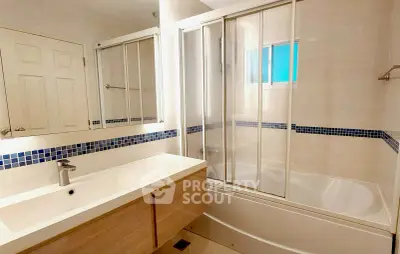 Modern bathroom with sleek fixtures and glass-enclosed bathtub in a bright, stylish setting.
