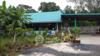 Charming rural home with blue roof and lush garden, perfect for nature lovers seeking tranquility.