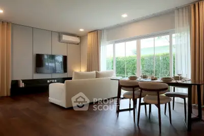 Spacious living room with modern decor and large windows offering garden views.