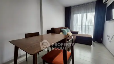 Modern living room with cozy sofa and dining table, featuring large window for natural light.