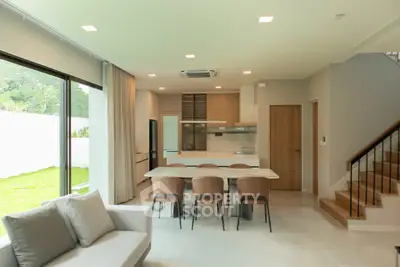 Modern open-plan kitchen and dining area with large windows and garden view.