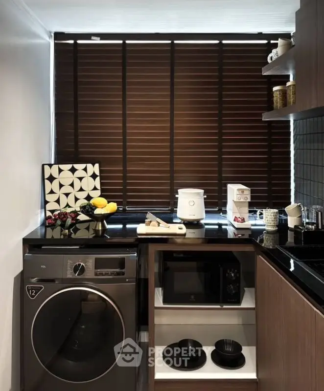 Modern kitchen with sleek appliances and stylish decor, featuring a washing machine and microwave.