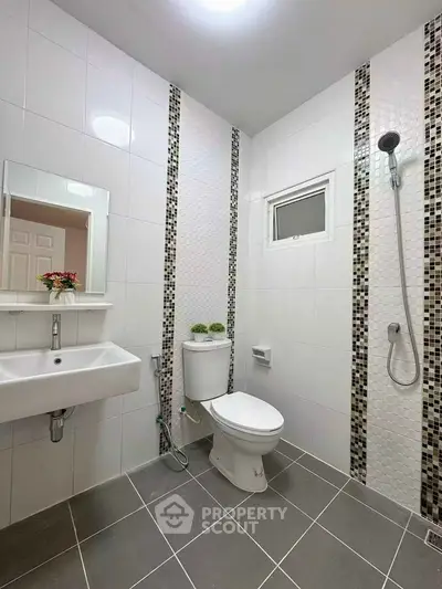 Modern bathroom with sleek tiles and contemporary fixtures, featuring a shower and elegant sink.