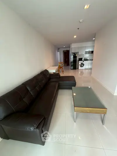 Spacious modern living room with sleek leather sofa and open kitchen layout