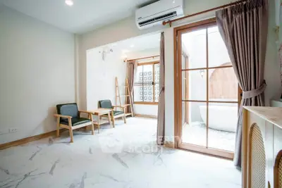 Spacious living room with elegant marble flooring and large windows opening to a private balcony.