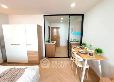 Modern studio apartment with stylish kitchen and dining area, featuring sleek furniture and elegant decor.