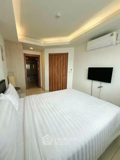 Modern bedroom with sleek design, featuring a comfortable bed, wall-mounted TV, and ambient lighting.