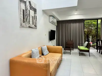 Spacious living room with modern decor and garden view, featuring a cozy sofa and stylish furniture.