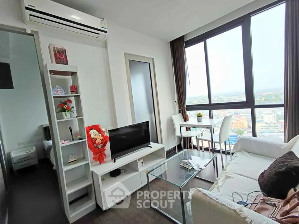 Modern living room with large windows and city view, featuring sleek furniture and stylish decor.