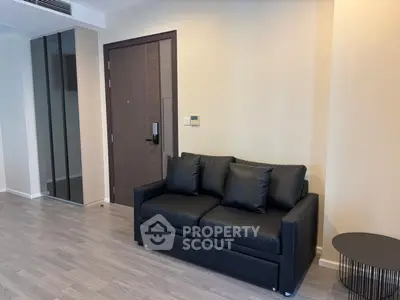 Modern living room with sleek black sofa and stylish side table in a minimalist apartment.
