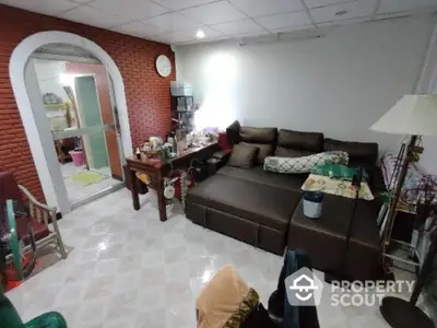 Spacious living room with a cozy brown sectional sofa, brick accent wall, and an arched doorway leading to another room, perfect for family gatherings.