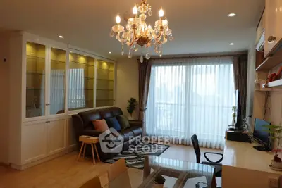 Elegant living room with chandelier, large window, and stylish furniture in a modern apartment.