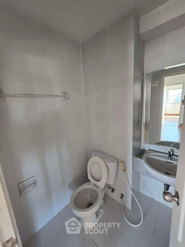 Compact bathroom with modern fixtures and white tiles, featuring a toilet and sink.