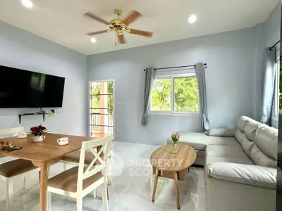 Bright living room with modern furniture and large windows offering garden views.