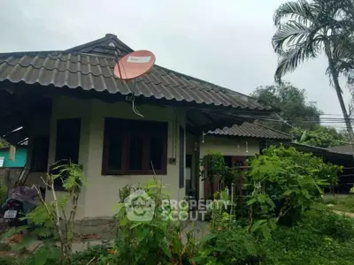 Charming single-story home with lush garden and satellite dish, perfect for serene living.