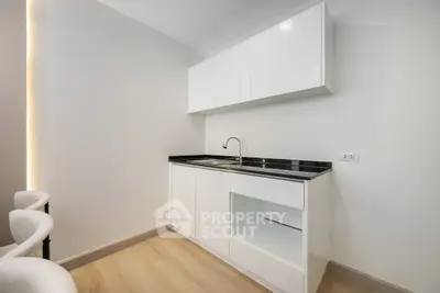 Modern minimalist kitchen with sleek white cabinets and black countertop, perfect for contemporary living.