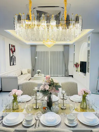 Luxurious dining and living area with elegant chandelier and floral decor