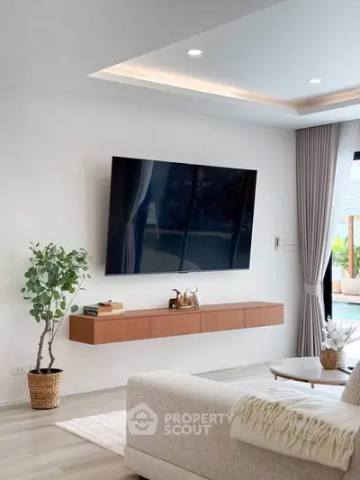 Modern living room with wall-mounted TV, sleek furniture, and pool view, perfect for relaxation and entertainment.