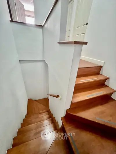 Elegant wooden staircase in modern home with sleek design and natural light.