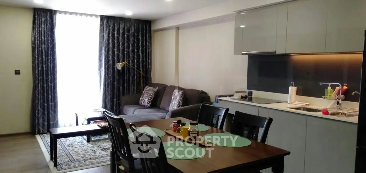 Modern open-layout living room with kitchen, featuring stylish furniture and elegant decor.