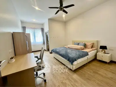 Spacious bedroom with modern decor and natural light, featuring a comfortable bed and work desk.