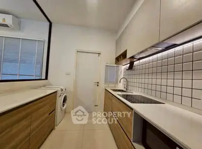 Modern kitchen with sleek cabinetry and built-in appliances, featuring a washing machine and stylish backsplash.
