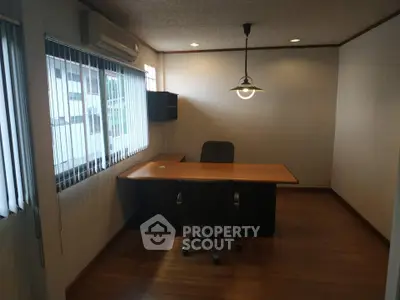 Spacious office room with wooden flooring and modern lighting, ideal for professional work environment.