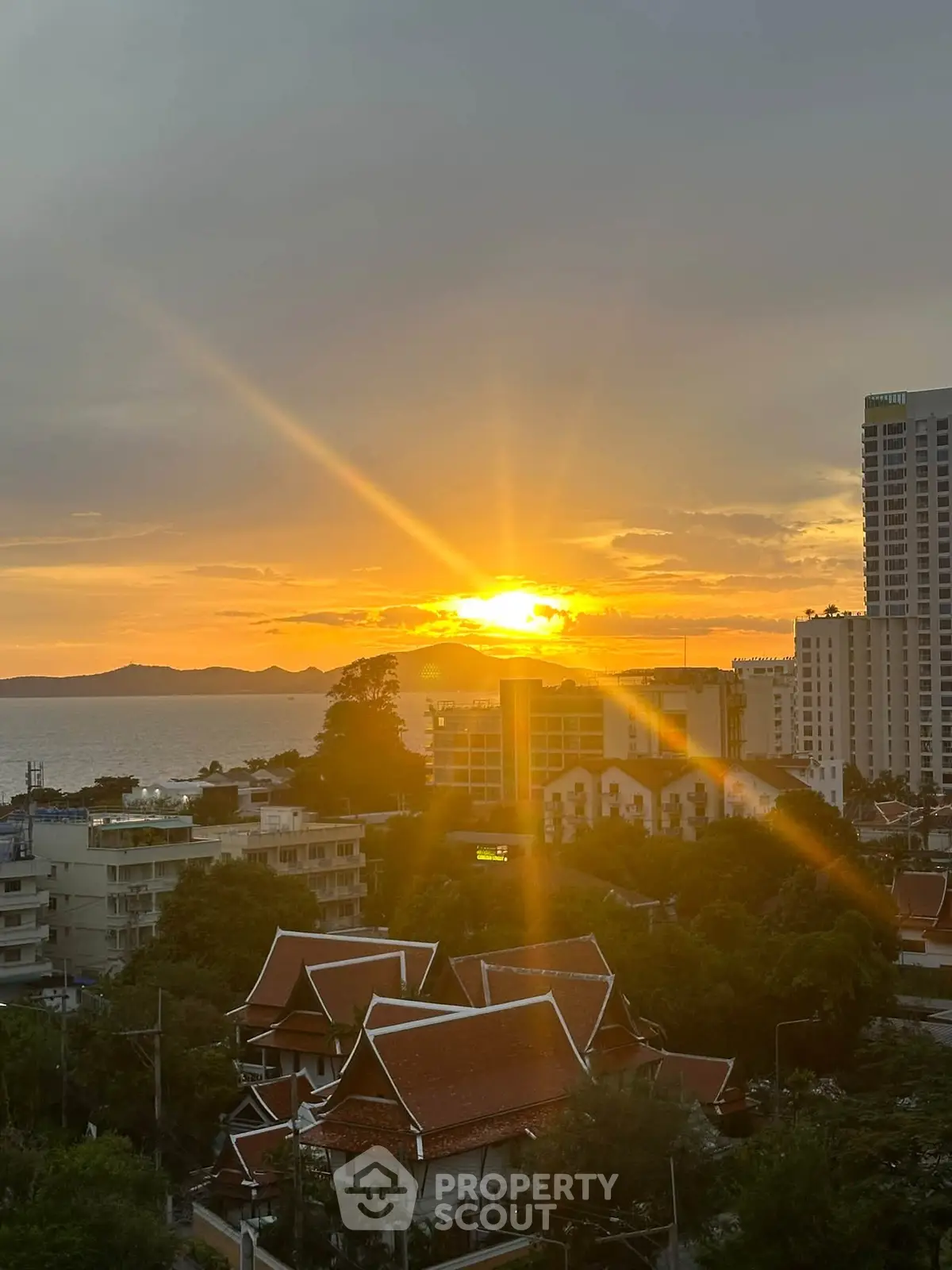 Stunning sunset view over cityscape with ocean horizon, perfect for high-rise living.