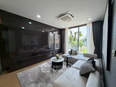 Modern living room with sleek design and large window offering natural light and garden view.