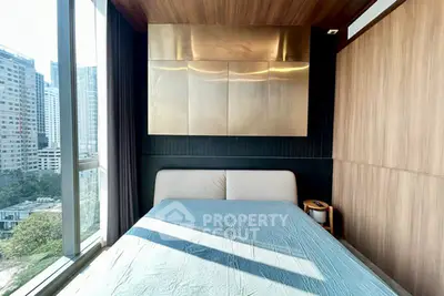 Modern bedroom with large window offering city view, featuring sleek wooden paneling and stylish decor.