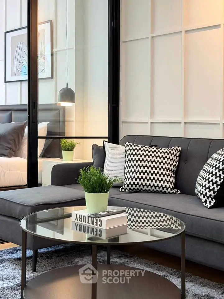 Modern living room with stylish decor and glass partition to bedroom