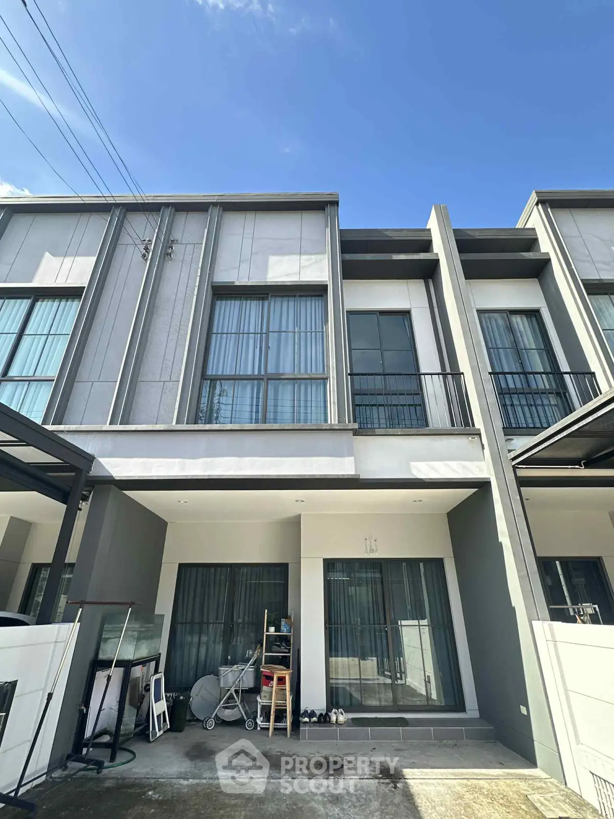 Modern townhouse exterior with large windows and sleek design in a sunny neighborhood.