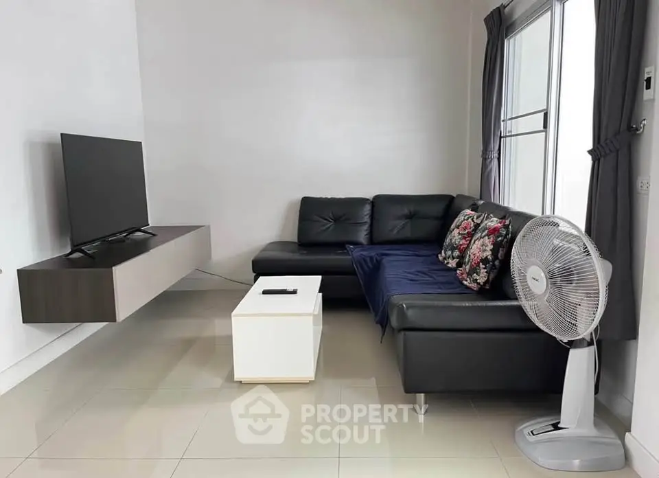 Modern living room with sleek black sofa, wall-mounted TV, and elegant decor.