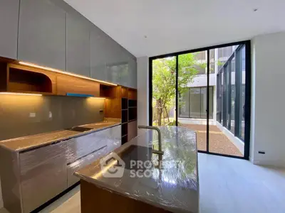 Modern kitchen with sleek cabinetry and large glass doors opening to a serene courtyard view.