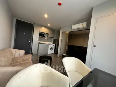 Modern living room with open kitchen, featuring washing machine and air conditioning.