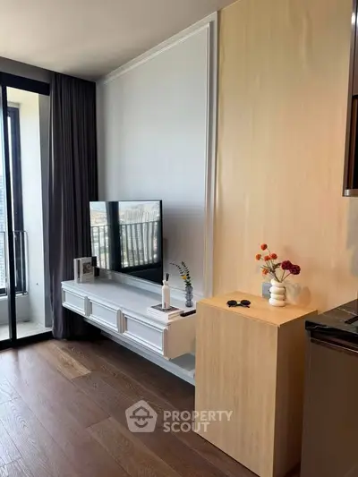 Modern living room with stylish decor and large window offering city views.