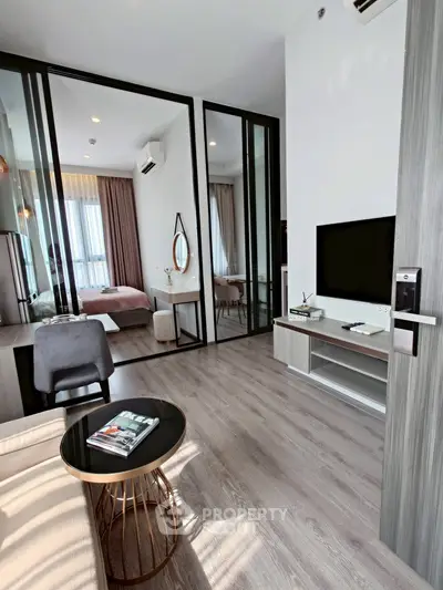 Modern apartment with open living room and bedroom, featuring sleek design and natural light.