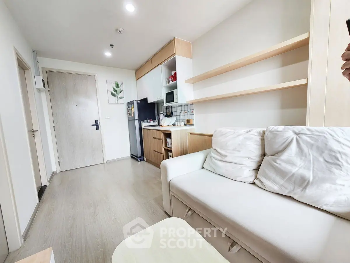 Modern living room with cozy sofa and open kitchen layout in stylish apartment.