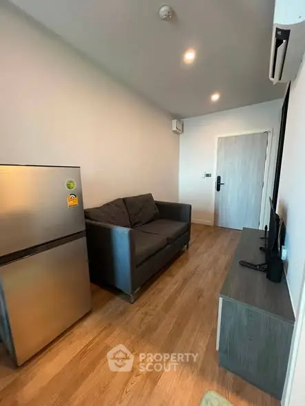 Modern living room with sleek furniture and wooden flooring, featuring a compact layout ideal for urban living.