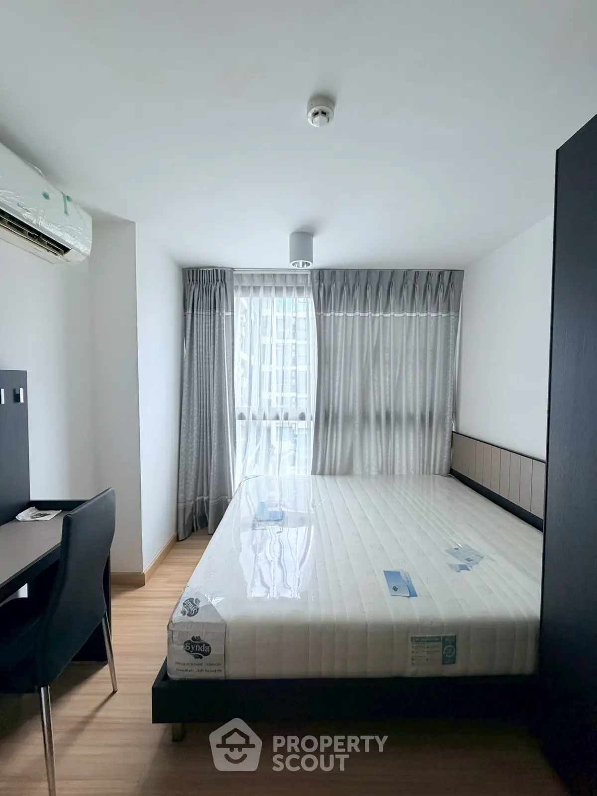 Modern bedroom with large window and minimalist furniture in a bright apartment.