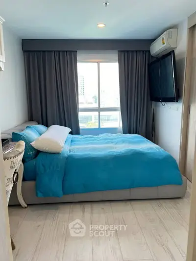 Cozy bedroom with modern decor and large window offering natural light.