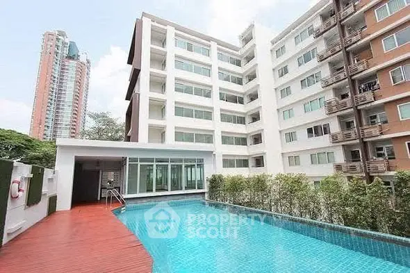 Modern apartment building with a luxurious swimming pool and spacious deck area.