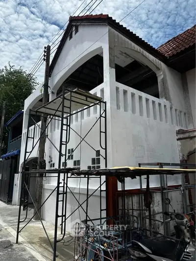 Under-construction house exterior with scaffolding and red roof tiles