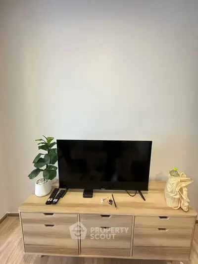 Modern living room with sleek TV setup on wooden cabinet, minimalistic decor enhancing space.