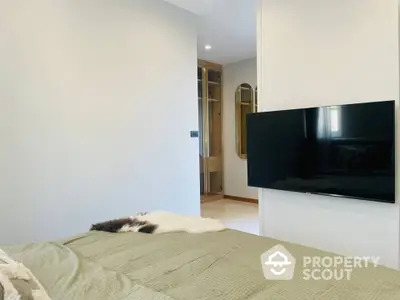 Cozy bedroom with modern wall-mounted TV, plush bedding, and elegant wooden door leading to a well-appointed ensuite.