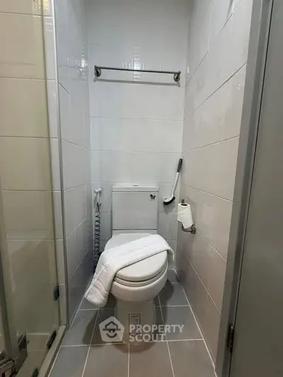 Compact bathroom with modern fixtures and tiled walls, featuring a toilet and towel rack.
