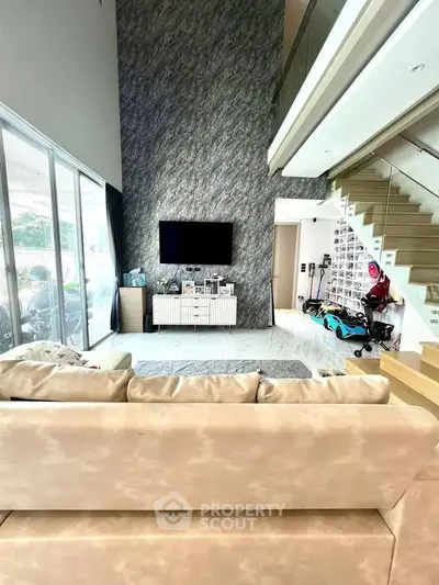 Spacious modern living room with high ceiling and elegant staircase