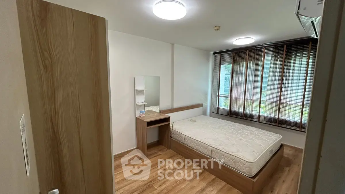 Modern bedroom with wooden flooring and large window for natural light