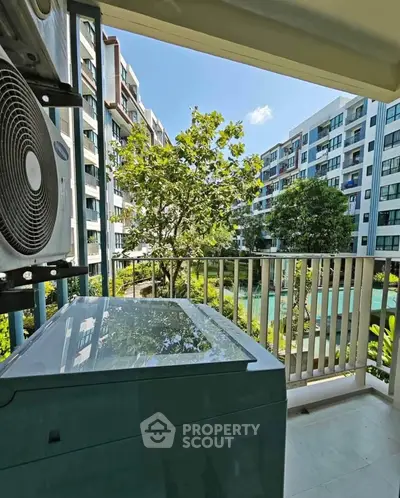 Modern apartment balcony with scenic view of lush garden and contemporary buildings.